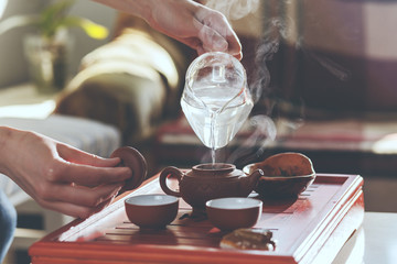 Die Teezeremonie. Die Frau gießt heißes Wasser in die Teekanne
