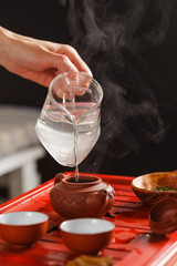 The tea ceremony. The woman pours hot water into the teapot