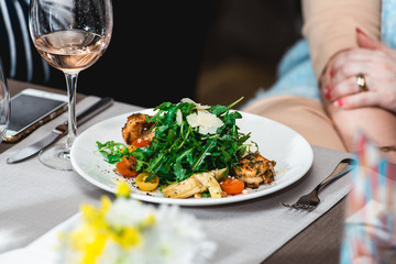woman eating delicious salad with shrimp in a restaurant