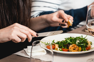 woman eating delicious salad with shrimp in a restaurant