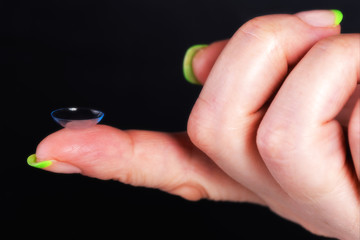 A soft contact lens on the female finger