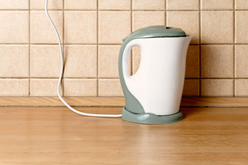 Electric kettle in front of tiled wall on table top