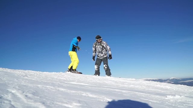 Two snowboarders help each other and then move out of the mountain