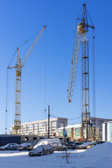 Fototapeta na wymiar Construction cranes on site for construction of houses