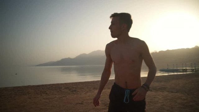 Man in a swimsuit running and throwing a frisbee slow motion