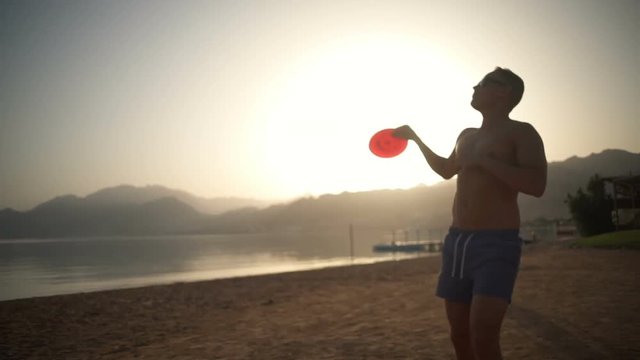 Man in a swimsuit catching a frisbee slow motion