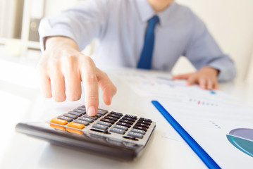 Fototapeta premium Businessman pressing calculator button at working table in the office