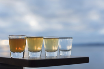 Close up four types of tequila on outside seaside deck