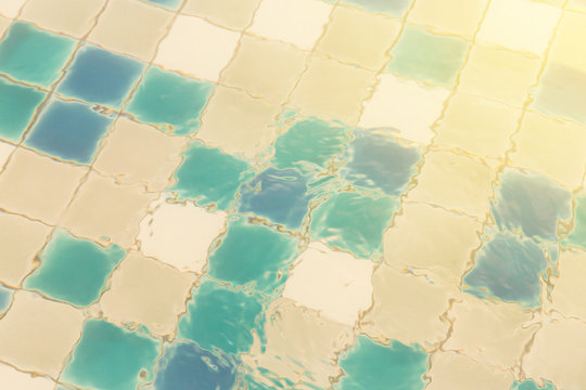 blue ripped water in swimming pool of the hotel. background of water refrection and swimming pool tiles. vintage photo and film style.