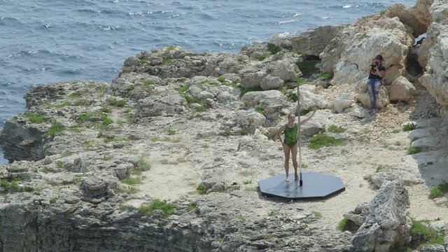 Photographer taking pictures of pole dancer during pole dance above the sea