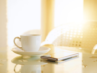 Coffee cup on table and smartphone with sunlight in morning