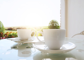 Coffee cup on table against nature background with sunlight