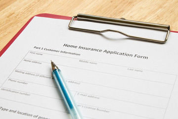 Home insurance application form with red file on wooden table
