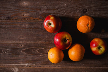 Apples and oranges on old wooden background. Bio food concept.