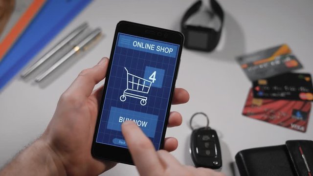 Shopping in an online store on your smartphone. The man has already chosen the goods, they are in the virtual basket, the finger presses the button to pay now, the transaction is successful.