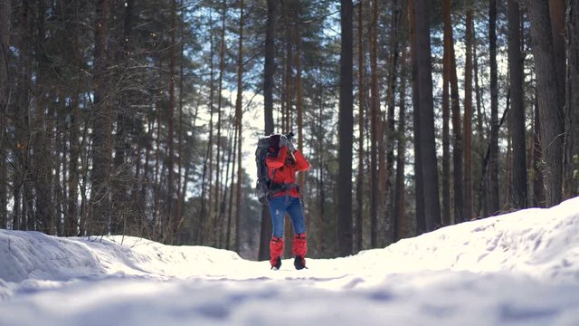 Beautiful young woman hiking with a backpack in beautiful winter forest. 4K.