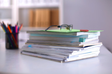 A stack of documentation is on the desktop in the office