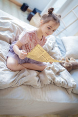 Obraz na płótnie Canvas Cute little girl reading a newspaper