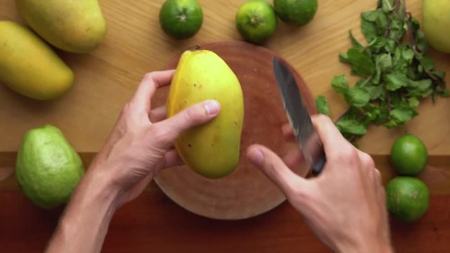 Man cuts a mango on peaces. Process of making a Juicy mango shake. Healthy life concept