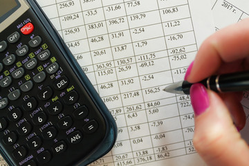 Financial analysis. Business concept. Womаn holding а pen calculates bookkeeping.