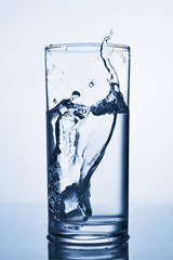 Ice cube dropped into the glass of water.