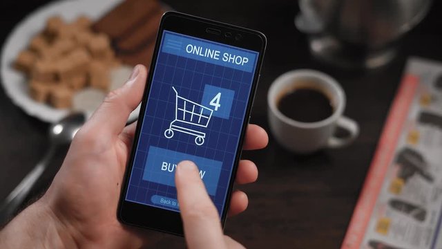 Shopping in an online store on your smartphone. The man has already chosen the goods, they are in the virtual basket, the finger presses the button to pay now, the transaction is successful.