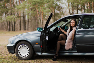 Portrait of a very beautiful girl in a forest dressed in fur in a car