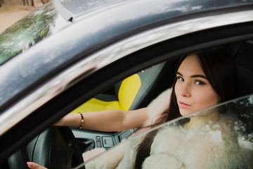 Portrait of a very beautiful girl in a forest dressed in fur in a car