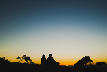 Fototapeta premium Two girls silhouettes at sunrise in Brazil