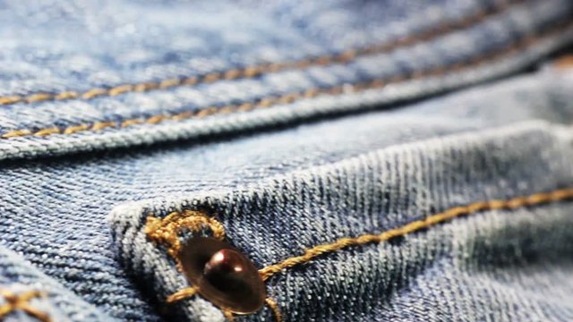 Extreme close-up tilt shot of the dark blue denim fabric of jeans with bright ye