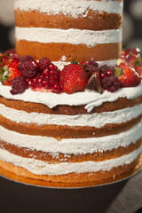 Naked cake on the gray background. Cake with fresh berries and white cream close up. holiday dessert concept.