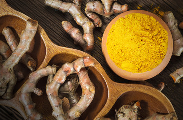 Turmeric roots on wooden background