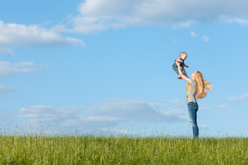 Mom walks with her baby. Mom throws baby up