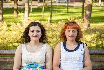 Two girls are sitting on a bench in the park 