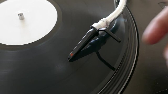 A moving shot of a person putting the spherical needle on a turning vinyl...