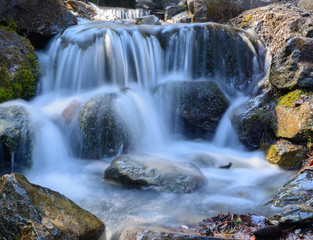 Fototapeta na wymiar Schöner idyllischer Wasserfall mit Felsen im Wald