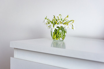 spring flowers in a vase on light table in white room