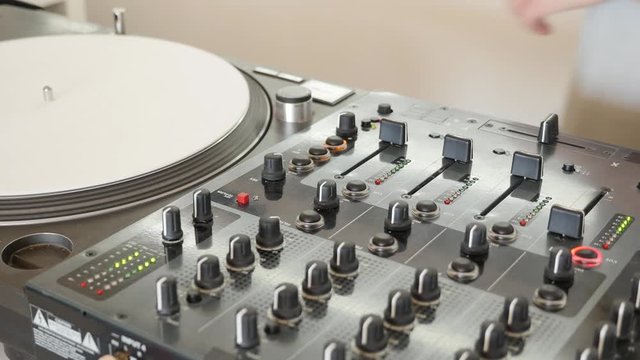 A person changes the vinyl and mixes music on an audio mixer...