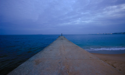 Jetty at the sunset with the blue ocean in  background. Cascais in Portugal