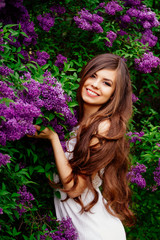 Naklejka premium a young girl by the lilacs in the spring , flowering gardens , a touch of spring