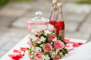 Delicate bride's bouquet on the table next to red lemonade . Wedding decorations