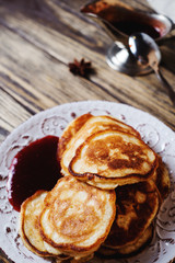 Hearty and tasty breakfast or lunch, fried pancakes with strawberry jam, milk and black tea on a dark wooden background 