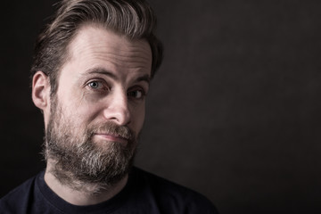 Dark moody close up portrait of happy caucasian man