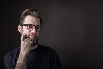Thoughtful caucasian man in casual t-shirt and glasses