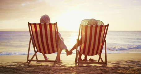 Happy retired couple enjoying beautiful sunset at the beach