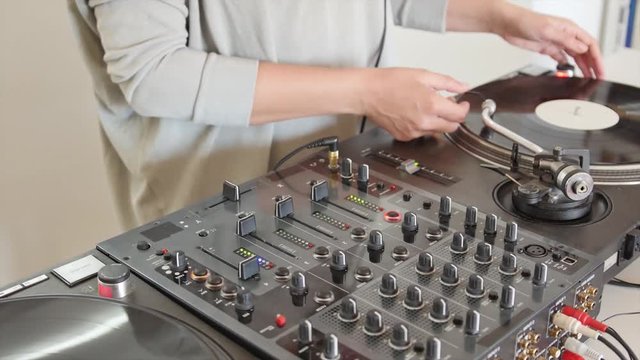 Footage of a person practicing mixing music on an audio mixer at home...