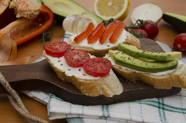 Slices of toasted bread with cherry tomatoes, peppers and avocado