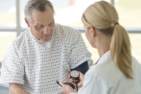 Female doctor taking senior man's blood pressure