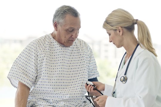 Female doctor taking senior man's blood pressure