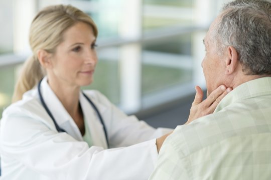 Female doctor touching senior man's neck